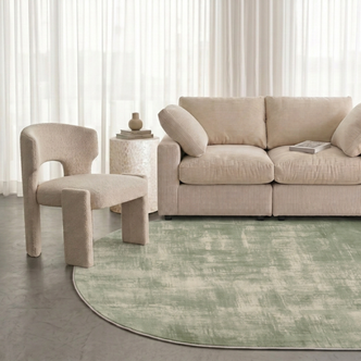 Sage green rug styled in a modern living room with a sofa, chair, and side table