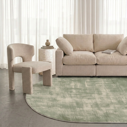 Sage green rug styled in a modern living room with a sofa, chair, and side table