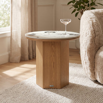 Round marble-topped side table beside a sofa in a bright living room