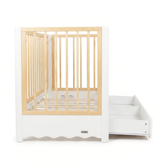 White and natural wood baby crib with pull-out storage feature on white background