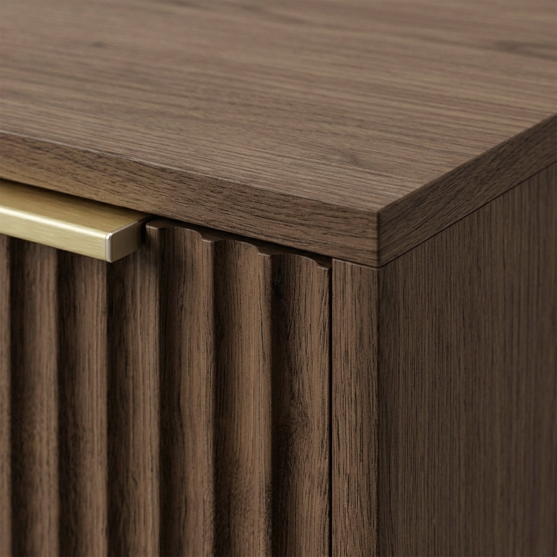 Close-up of the top corner of a walnut cabinet with fluted texture and metal handle