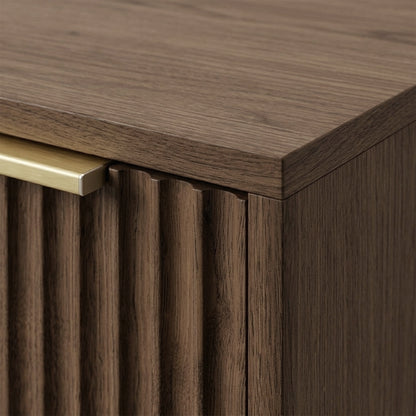 Close-up of the top corner of a walnut cabinet with fluted texture and metal handle