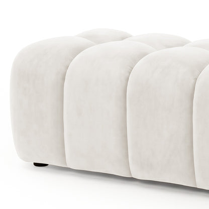 Light beige tufted upholstered ottoman bench partially cropped on a white background