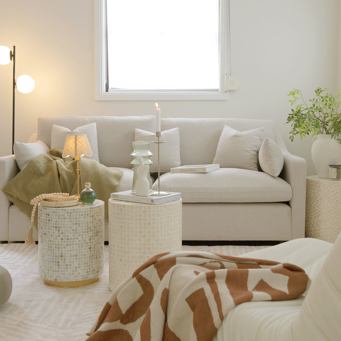 Neutral living room with light sofa, round tables, lamp, and decor