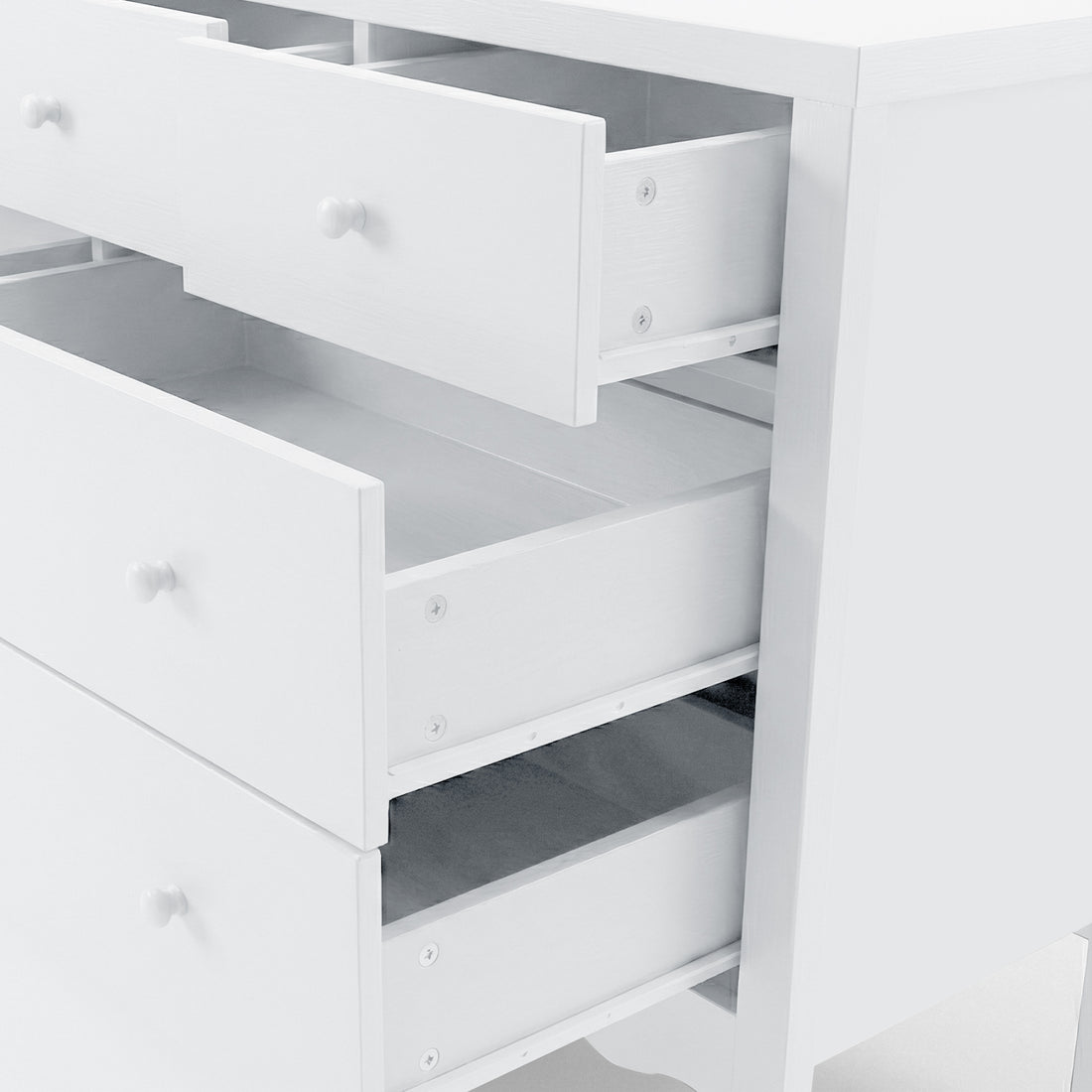 Angled, partial view of white chest of drawers with open drawers on white background