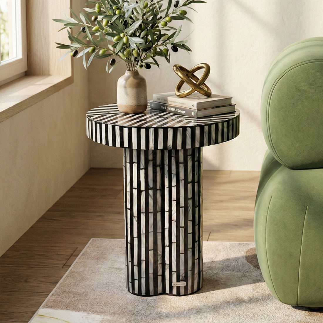 Black and white striped side table styled in a bright living room with green chair and decorative accessories