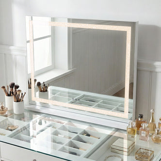 Lighted vanity mirror on a glass-topped vanity table with makeup accessories