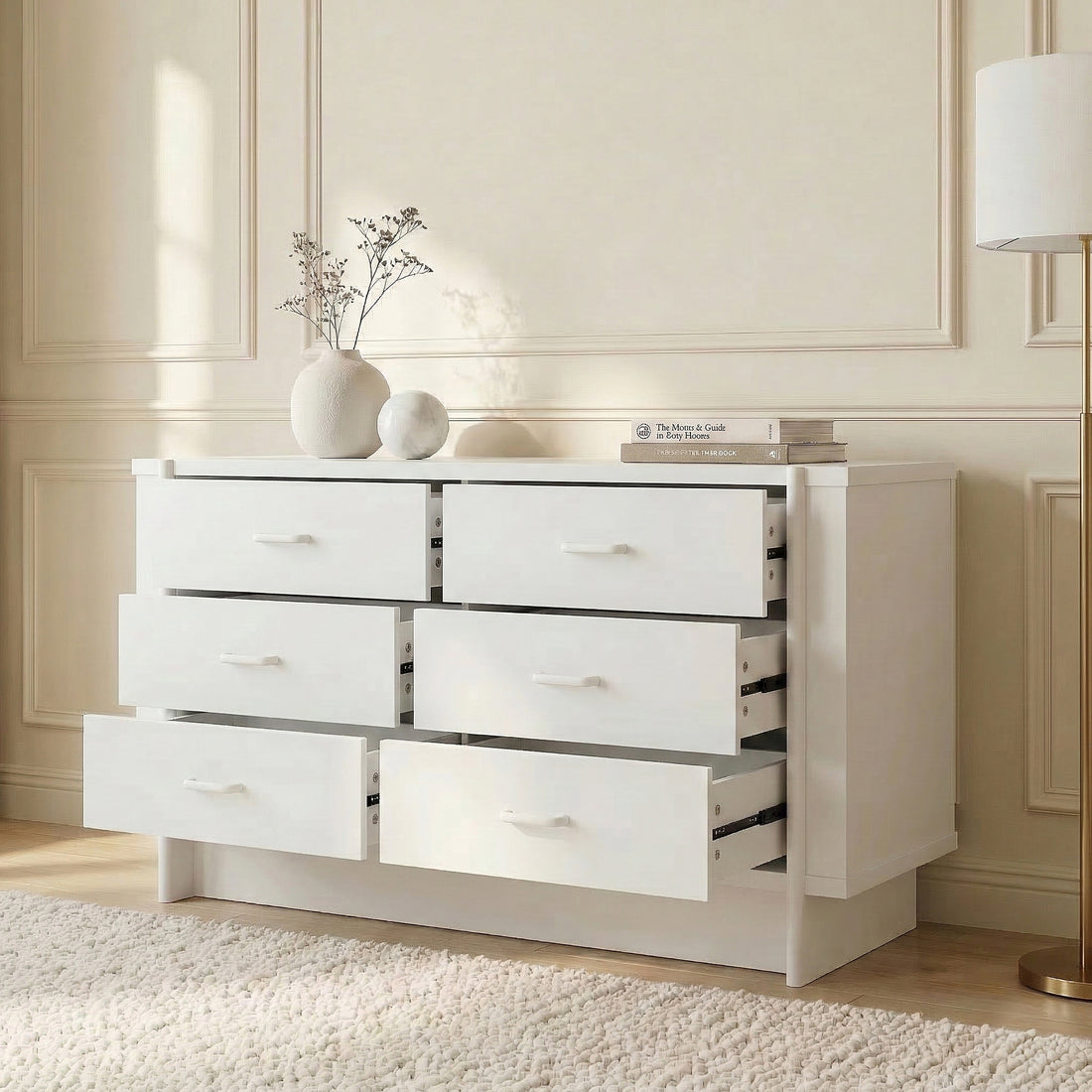 White dresser in an elegant room with partially open drawers, decorative books, and wall molding