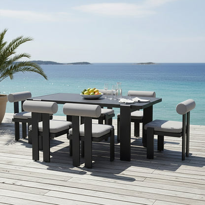 Positano 6 Seater Outdoor Dining Set in Black & Grey on a deck, featuring a rectangular table, six padded chairs, a fruit bowl, glassware, and a potted palm, overlooking the sea.