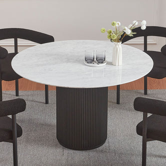 Gracie 120cm Round Marble Dining Table in Black with a fluted cylindrical base, topped with a small white vase and tray with glasses, surrounded by four low-back upholstered chairs.
