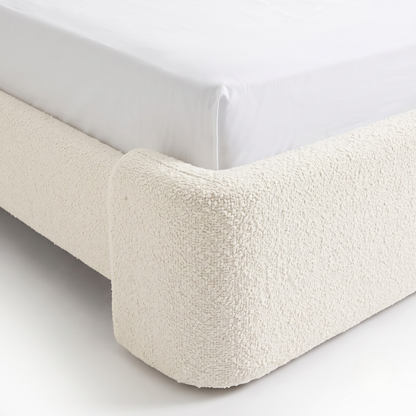 Close-up of upholstered bed corner on white background