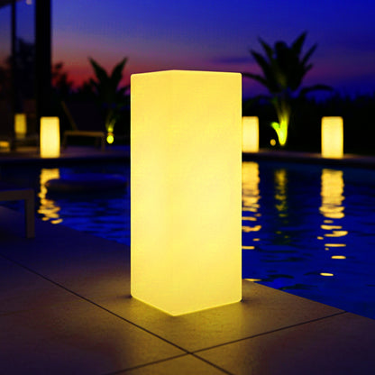 Colour Changing LED Column Light Indoor & Outdoor glows warmly poolside at twilight, reflecting off the water. More lamps line the pool, enhancing the tranquil evening atmosphere with ambient light.