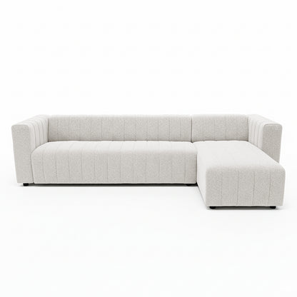 Parisa 4 Seater Tufted Boucle Sofa with Chaise in Cream White features an L-shaped design, clean squared-off arms, low black feet, and a right-side chaise, showcasing a modern, textured aesthetic.