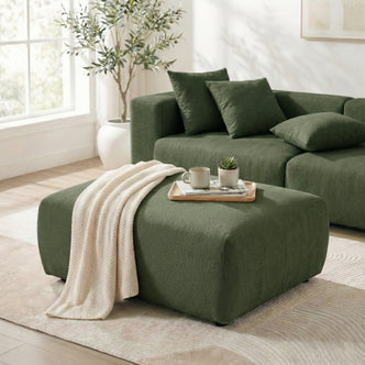 Green ottoman styled with a knit throw and tray in a bright living room