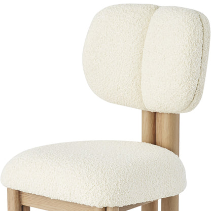 Norii Boucle Fabric Dining Chair in Cream White features a light-wood frame, cream bouclé upholstery, two cushioned backrests, and a rounded seat, offering modern elegance and comfort.