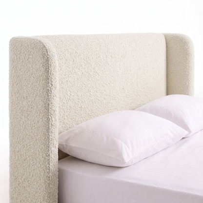 Partial view of upholstered bed on white background