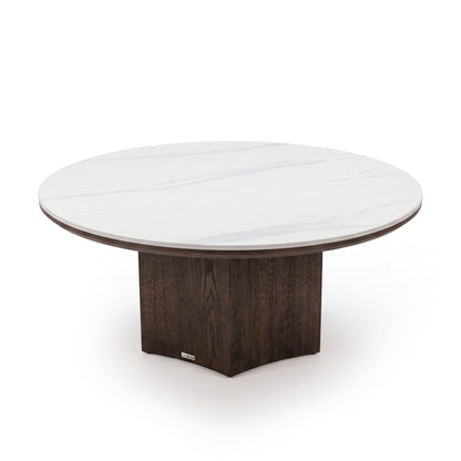 Modern round table with a white marble-effect top and dark square pedestal base on a white background