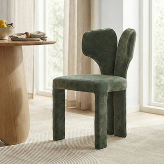 Green upholstered chair beside wooden table with fruit in bright room