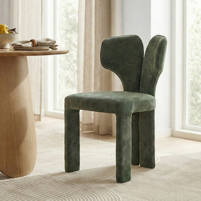 Green upholstered chair beside wooden table with fruit in bright room
