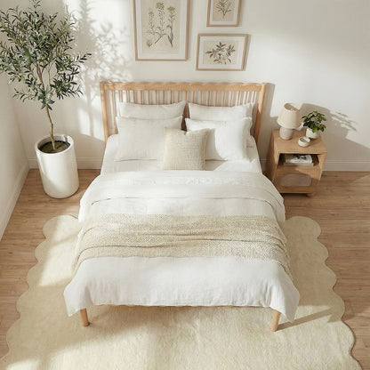 Light wood bed in modern bedroom with botanical wall art and potted plant