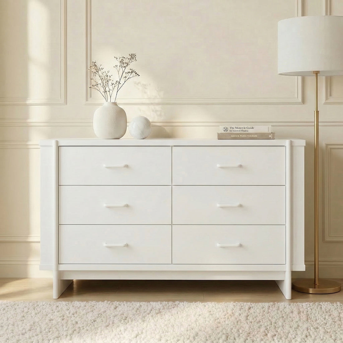 White dresser styled in a bright room with decorative vases and gold floor lamp