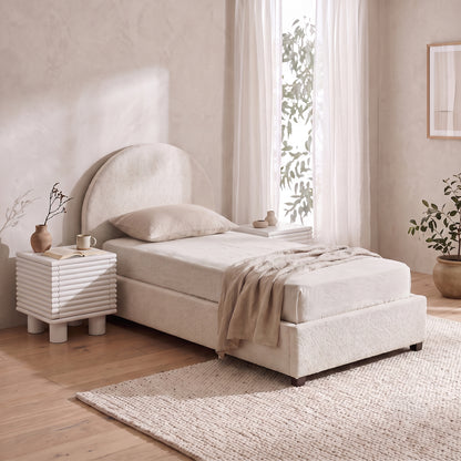 Cream bouclé single bed with an arched headboard and matching textured nightstand.